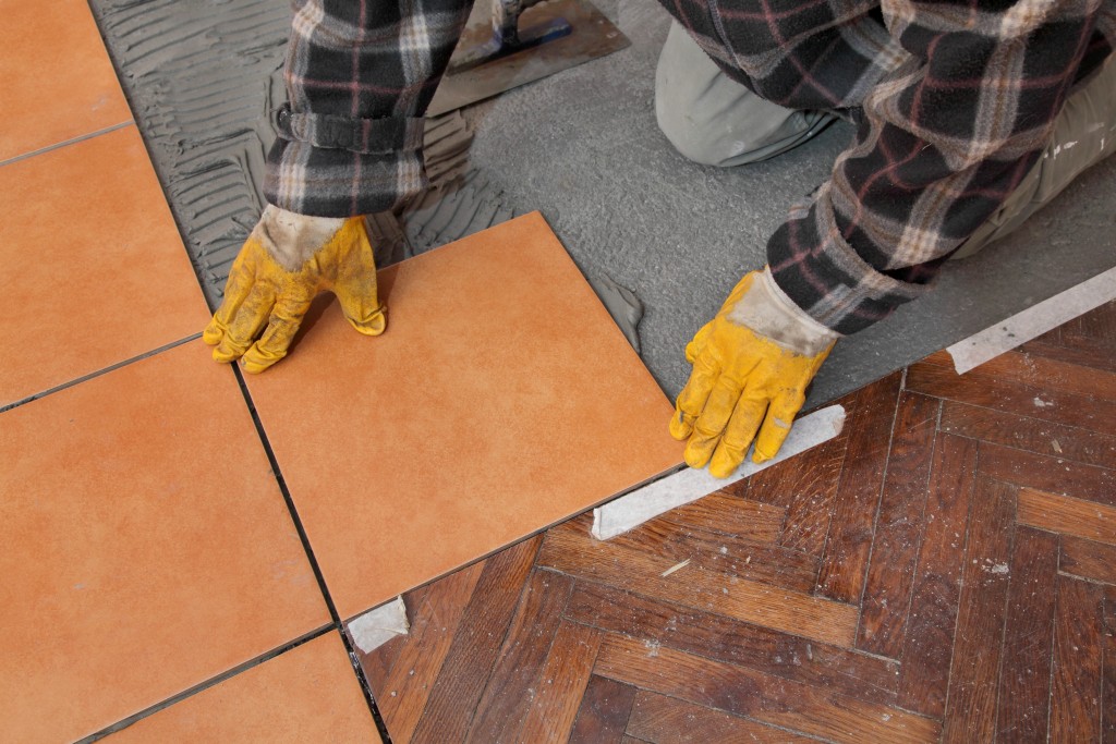 man installing new flooring tiles