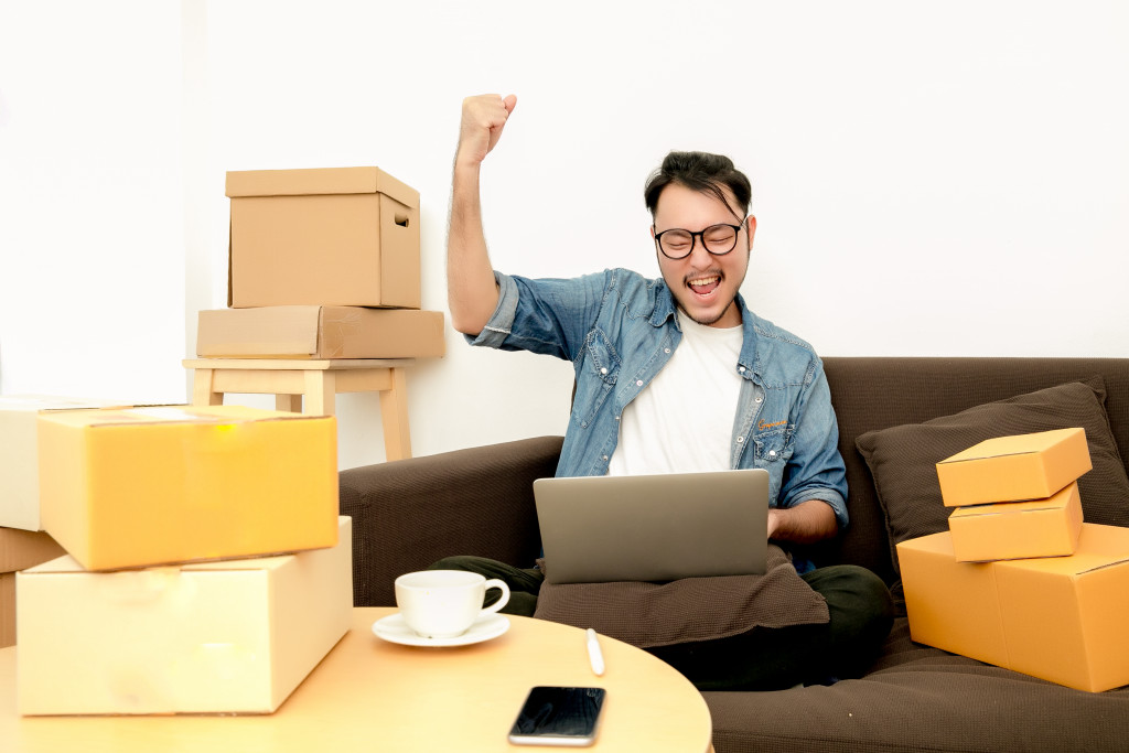 a business owner throwing his hands in the air while surrounded by packages