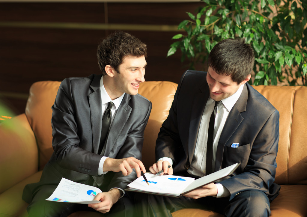 Image of two young businessmen discussing project at meeting