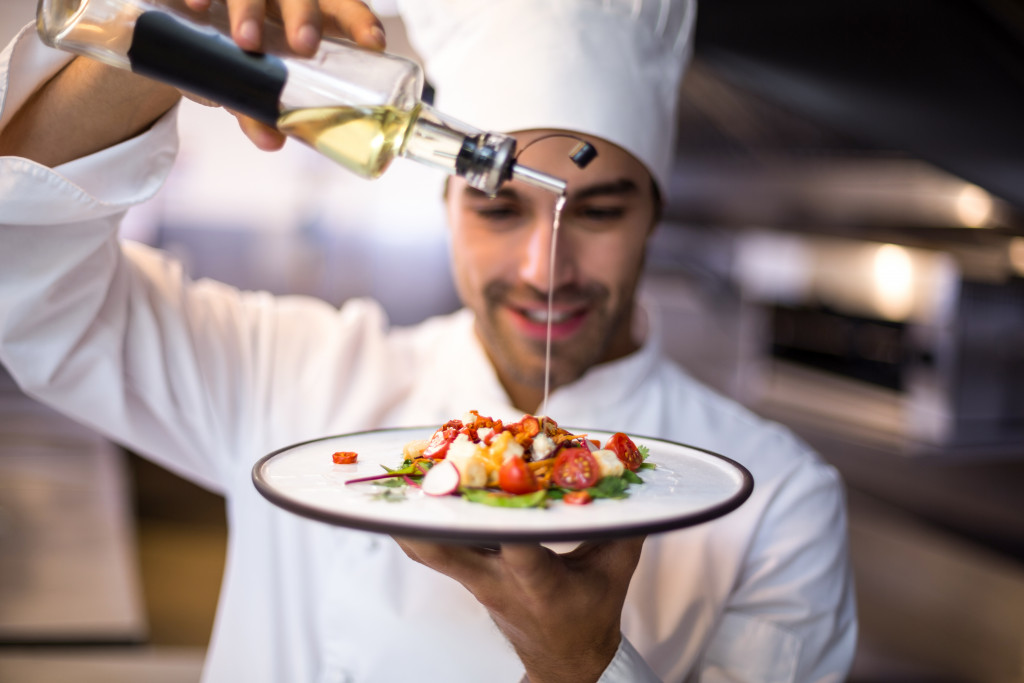 A chef pouring olive oil into a salad
