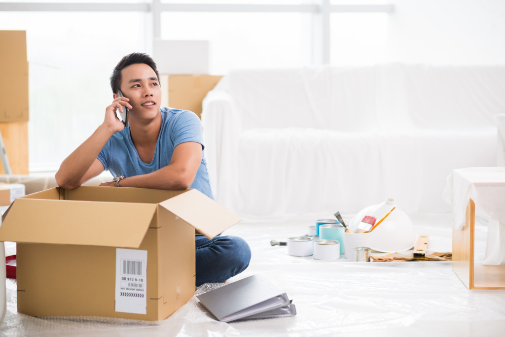 Young man talking on his phone and unpacking in his new home
