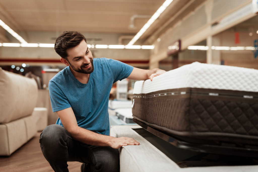 a man touching a mattress and bed in a store