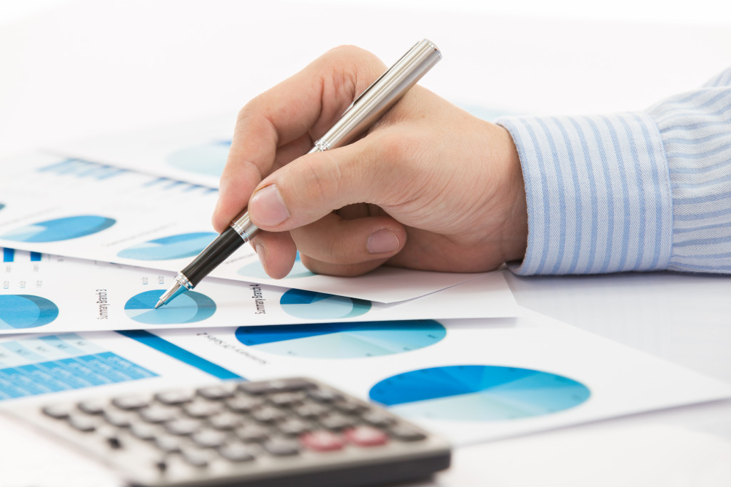 A hand holding a pen and using a calculator to analyze research data