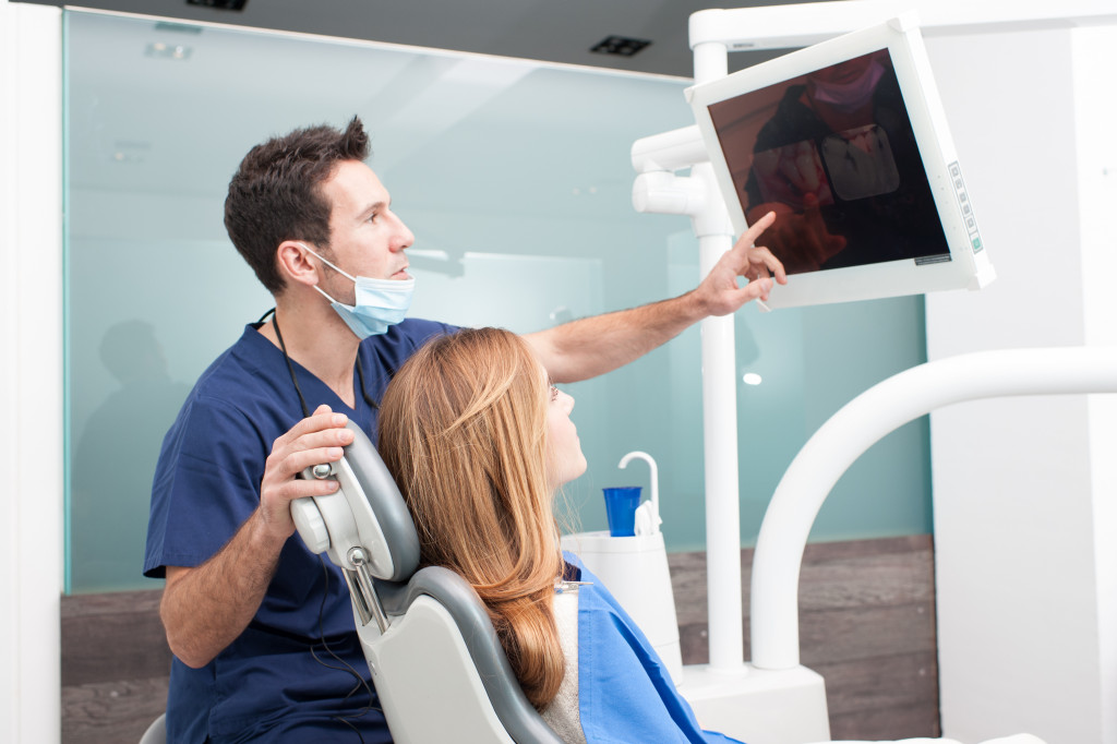 Dentist with a patient showing her results on a monitor screen