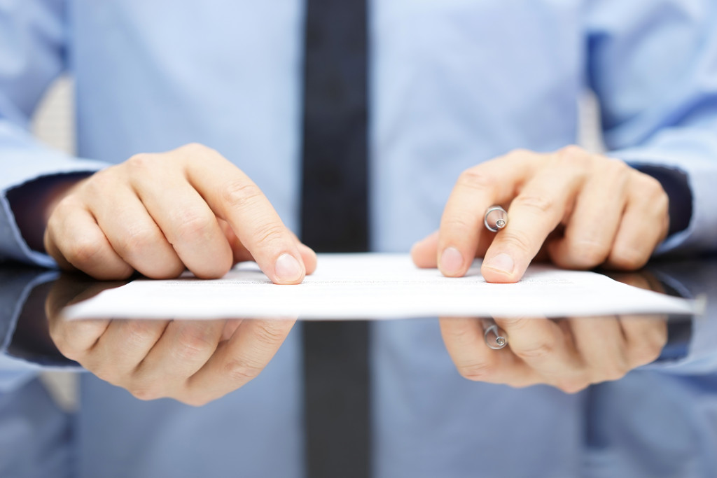 A person reading a contract document on a glass table