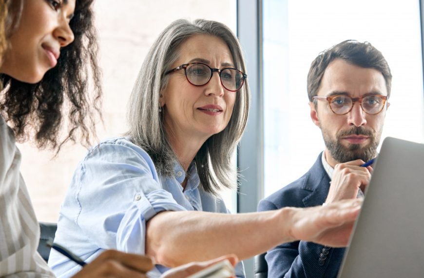 A mature businesswoman with colleagues in a meeting room