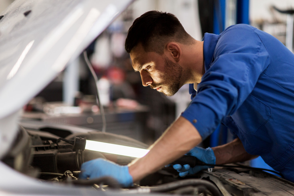  auto mechanic man with lamp working at workshop