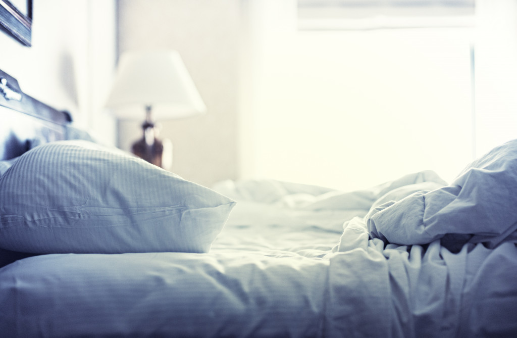 A cozy but ruffled blue bed in the morning light