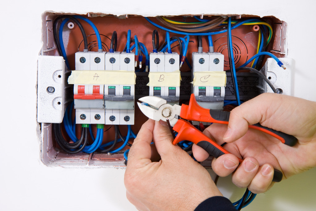 An electrician using pliers to fix an electrical wiring