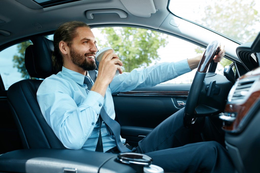 young businessman drinking coffee while driving