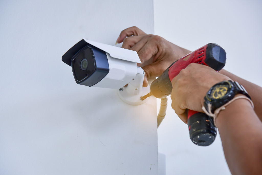 A hand using a drill to install a security camera