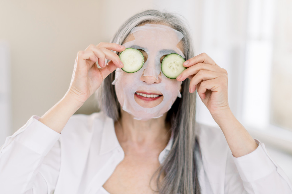 elderly woman with face mask and cucumbers in eyes