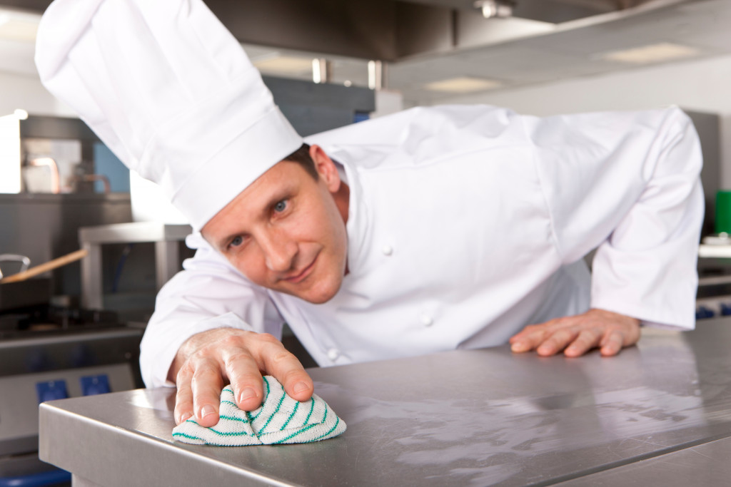 a male chef wiping a stainless steel countertop