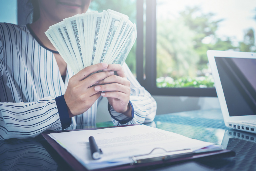 A woman holding a bunch of money, investing on a business