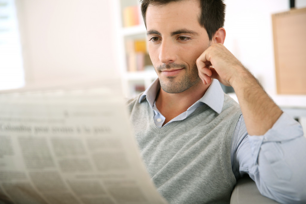 a man on a sofa holding a newspaper