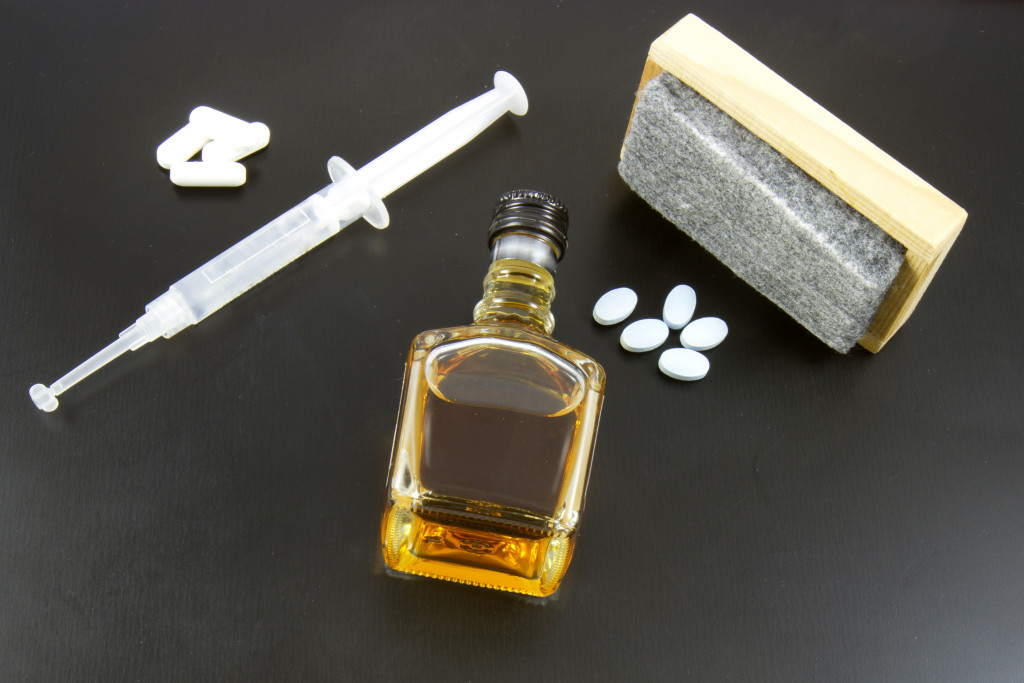 pills syringe and alcohol bottle on blackboard with eraser