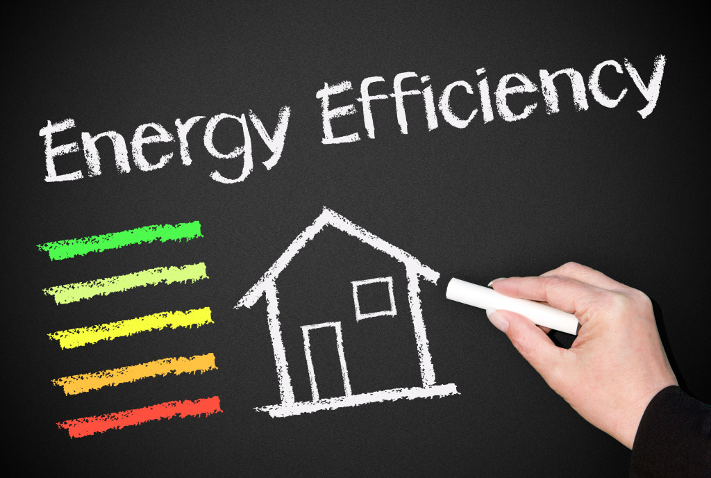 The words energy efficiency on a blackboard with multi-colored lines drawn beside a drawing of a house.