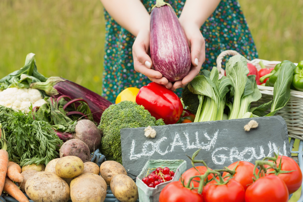 Woman holding an aubergine above a table full of vegetables