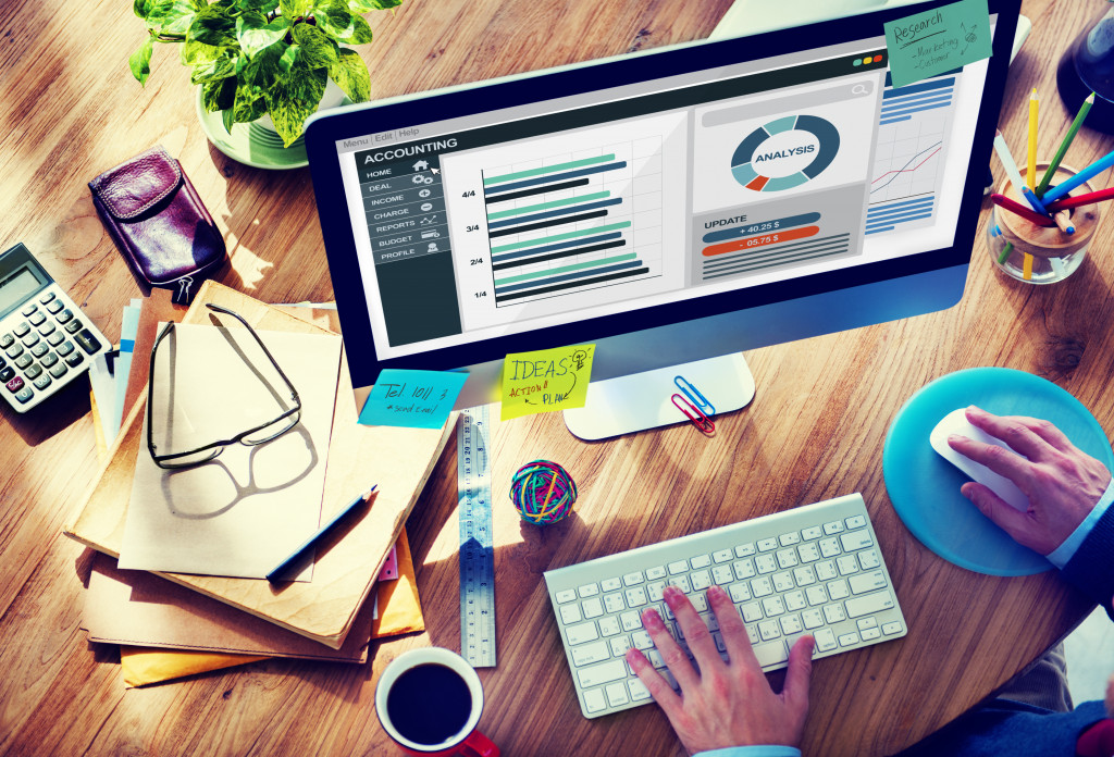 man with his desktop displaying graphs and charts