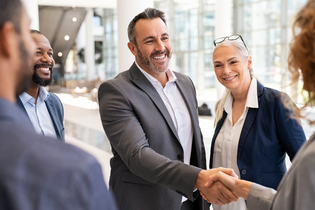 businessman smiling while shaking hands with another business person