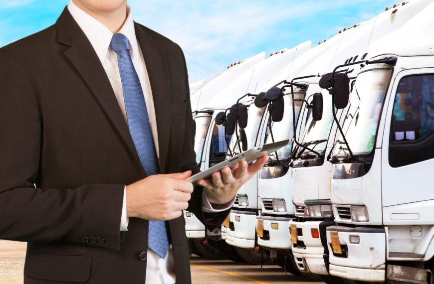 businessman holding tablet over row of trucks
