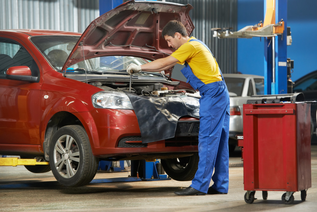 repair man with overalls repairing a red car