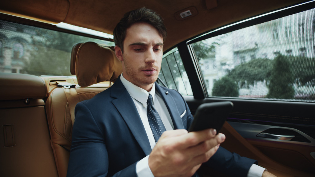 businessman using his phone inside the car