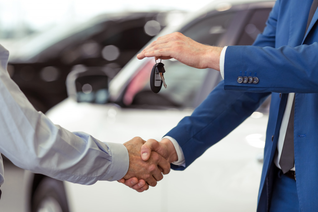 person handing car keys to another man in the dealership