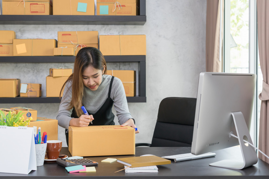 Young woman putting a label on a box for her home-based business.