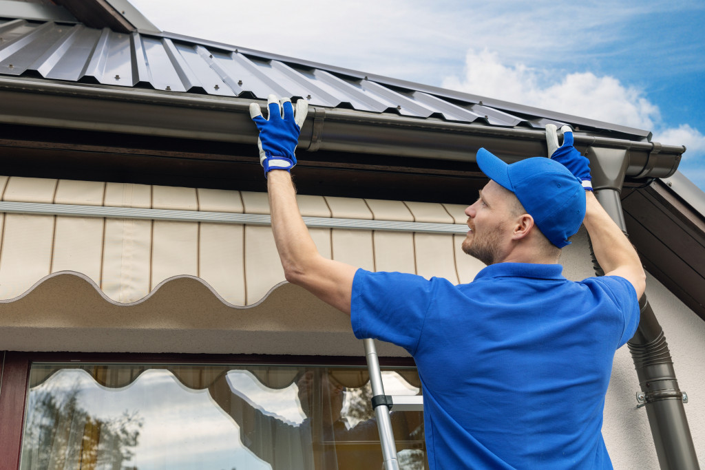 A worker repairing a roof gutter